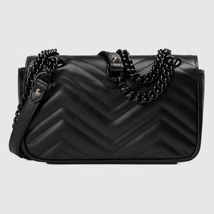 Black quilted handbag with chain detail on a light gray background