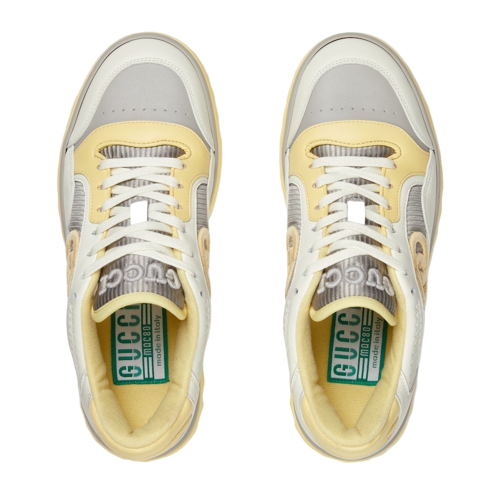 Pair of Gucci sneakers with yellow soles and gray uppers on a white background