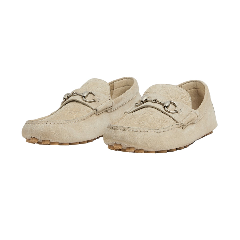 Pair of beige loafers with a decorative buckle on a light gray background