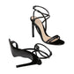 Black high-heeled sandals with strappy design on a light gray background