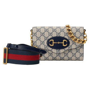 Designer handbag with chain strap and matching belt on a light gray background