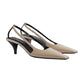 Pair of beige slingback heels with black straps on a light gray background