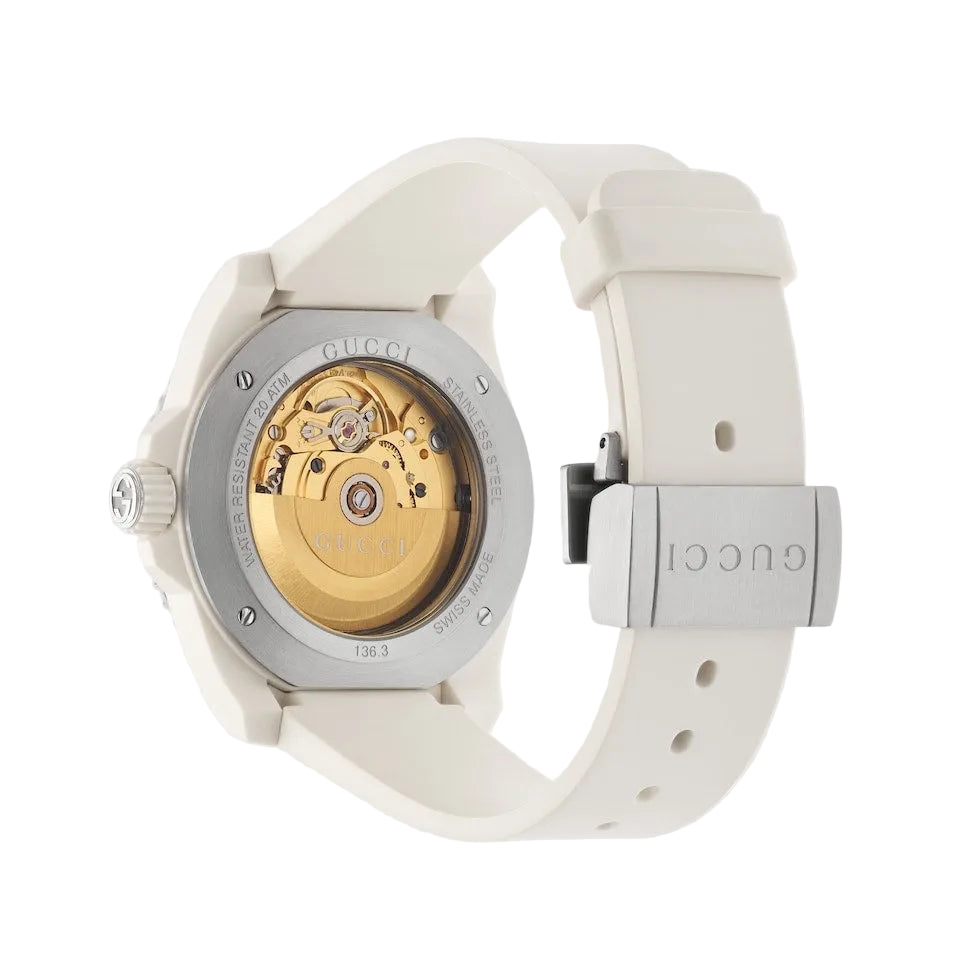 Gucci watch with white strap and gold mechanical face on a light gray background