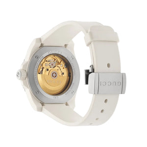 Gucci watch with white strap and gold mechanical face on a light gray background