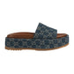 Blue denim slide sandal with brown sole on a light gray background