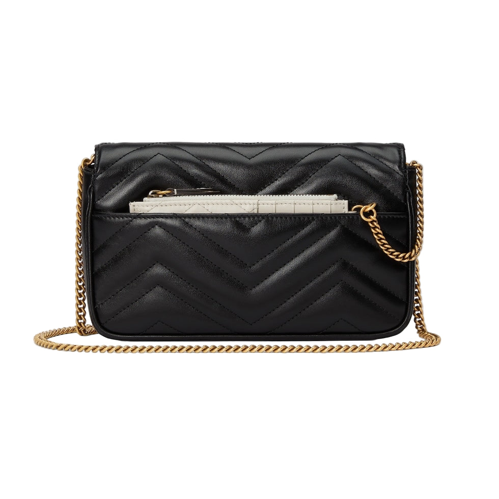 Black quilted handbag with gold chain strap on a light gray background
