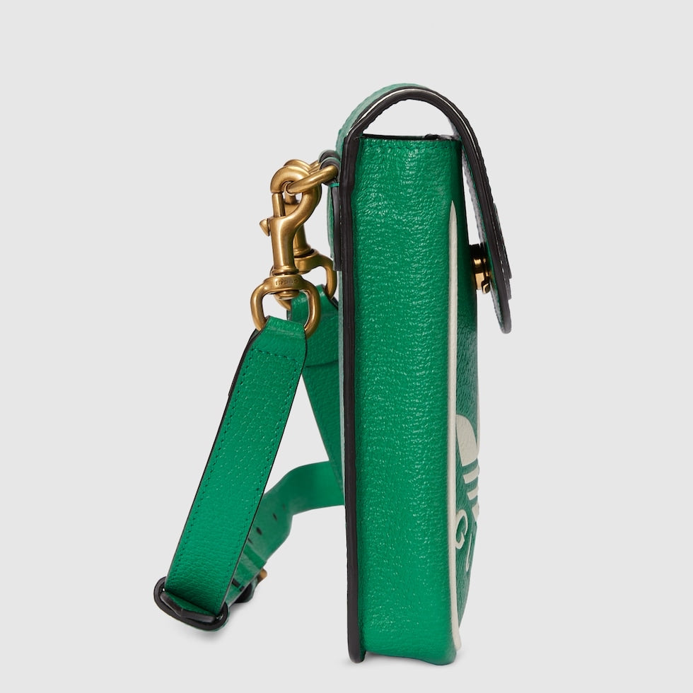 Green leather bag with gold clasp on a light gray background