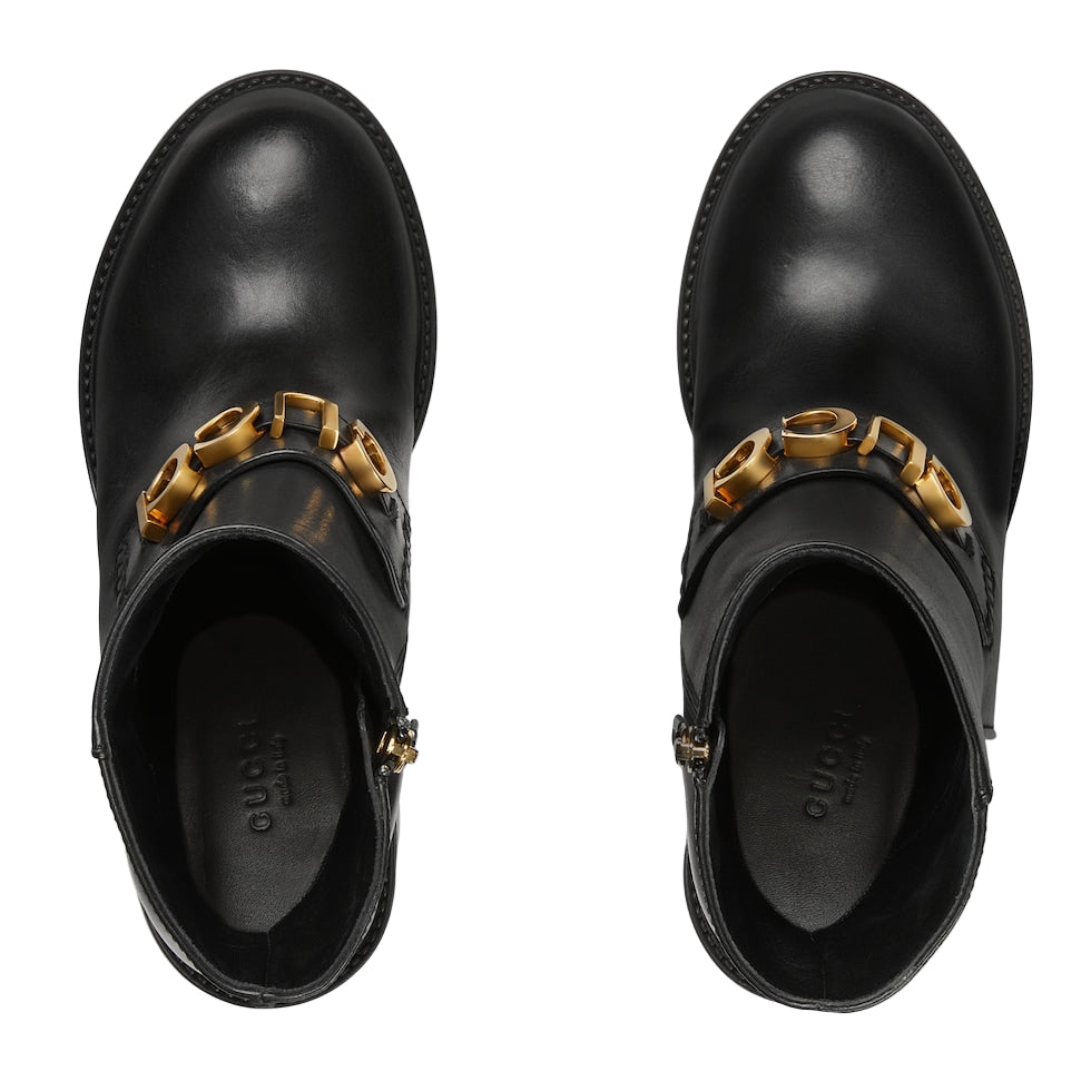 Black boots with gold chain details on a light gray background