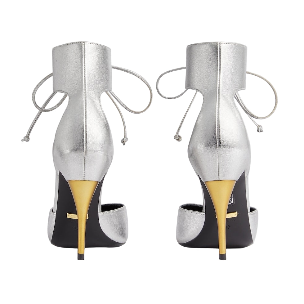 Pair of silver high-heeled shoes with yellow soles on a light gray background
