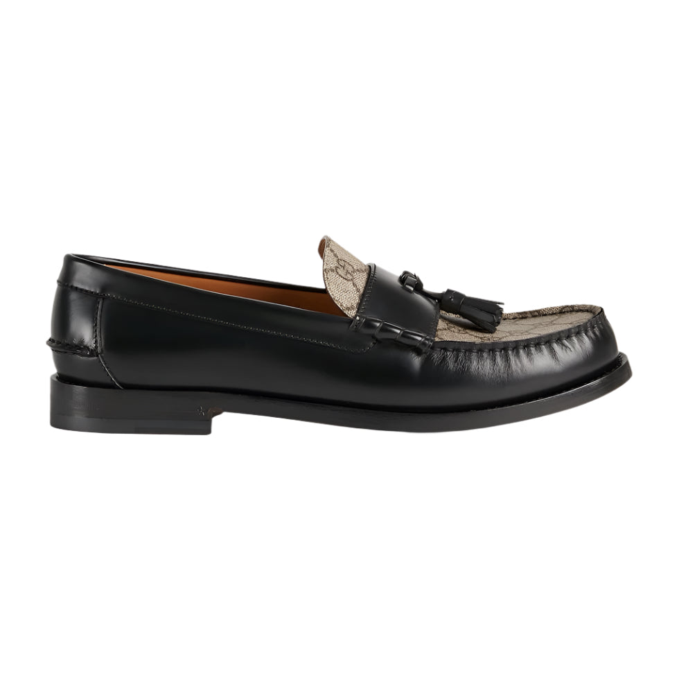 Black loafer shoe with tassel on a light gray background