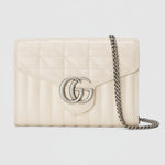 Cream-colored quilted handbag with chain strap on a light gray background
