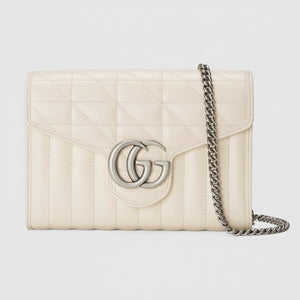 Cream-colored quilted handbag with chain strap on a light gray background