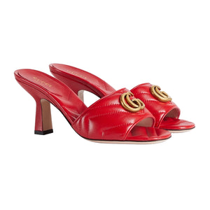 Red high-heeled shoes with gold Gucci logo on a light gray background
