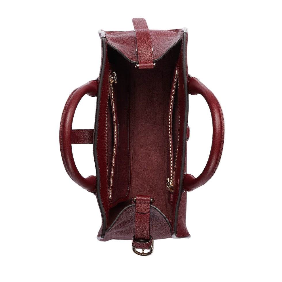 Maroon leather handbag with gold zipper on a light gray background