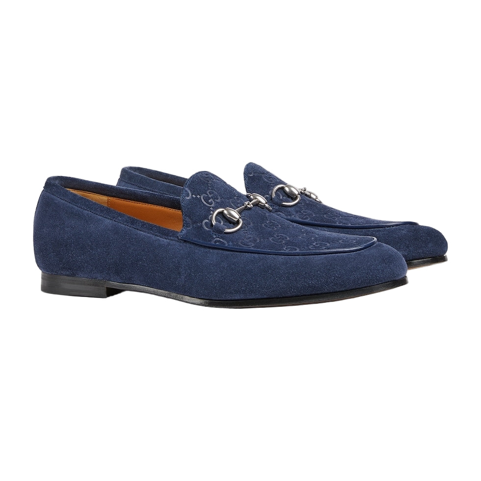 Pair of blue suede loafers with a decorative buckle on a light gray background