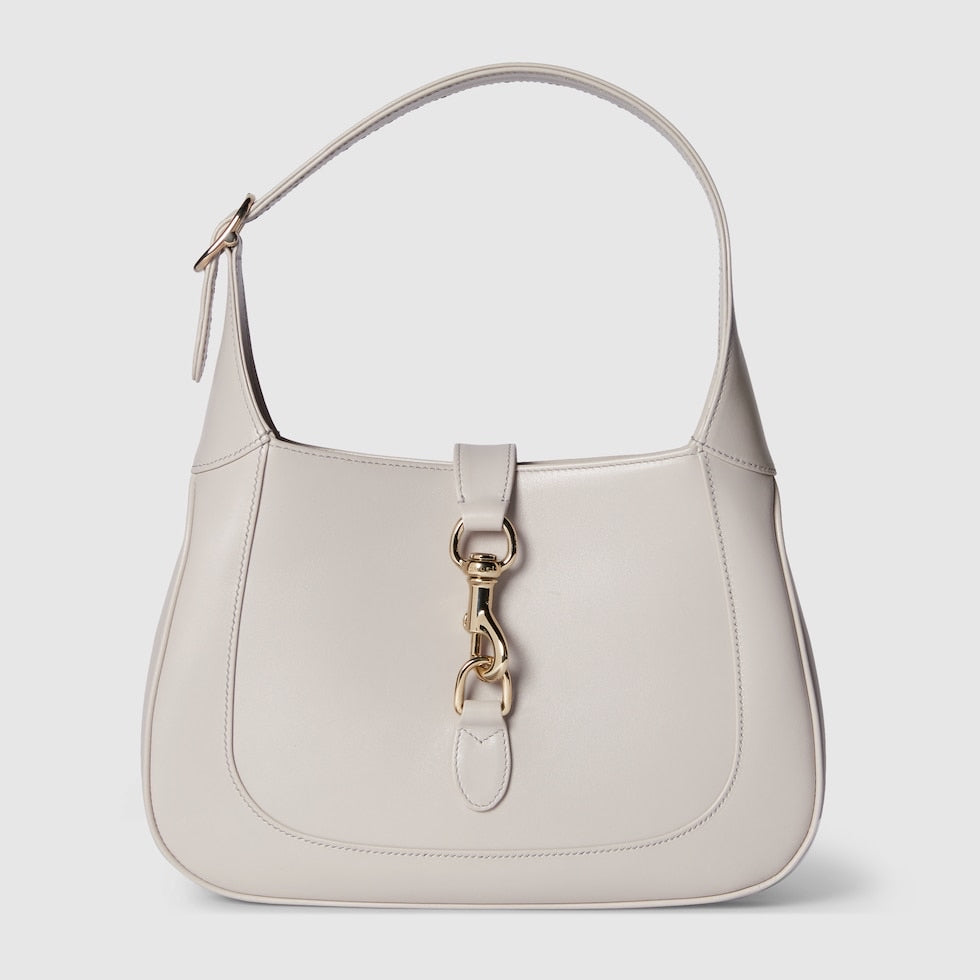 Light gray handbag with a gold clasp on a white background