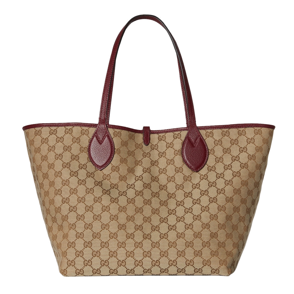 Beige handbag with brown pattern and red handles on a light gray background