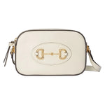 White handbag with gold emblem on a light gray background