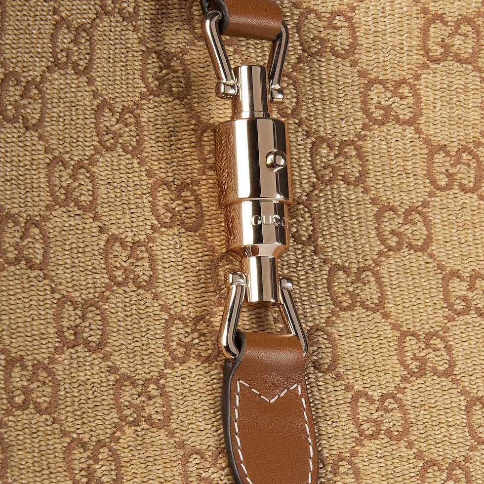 Close-up of a metallic clasp on a brown leather keychain against a patterned background
