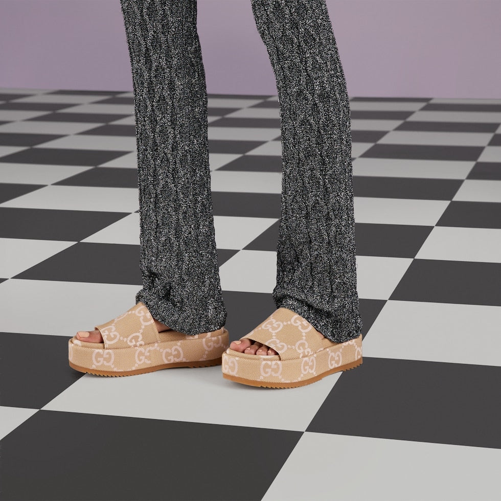 Person wearing beige sandals with a pattern on a checkered floor.