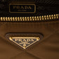 Close-up of a Prada handbag with gold accents and Prada logo.