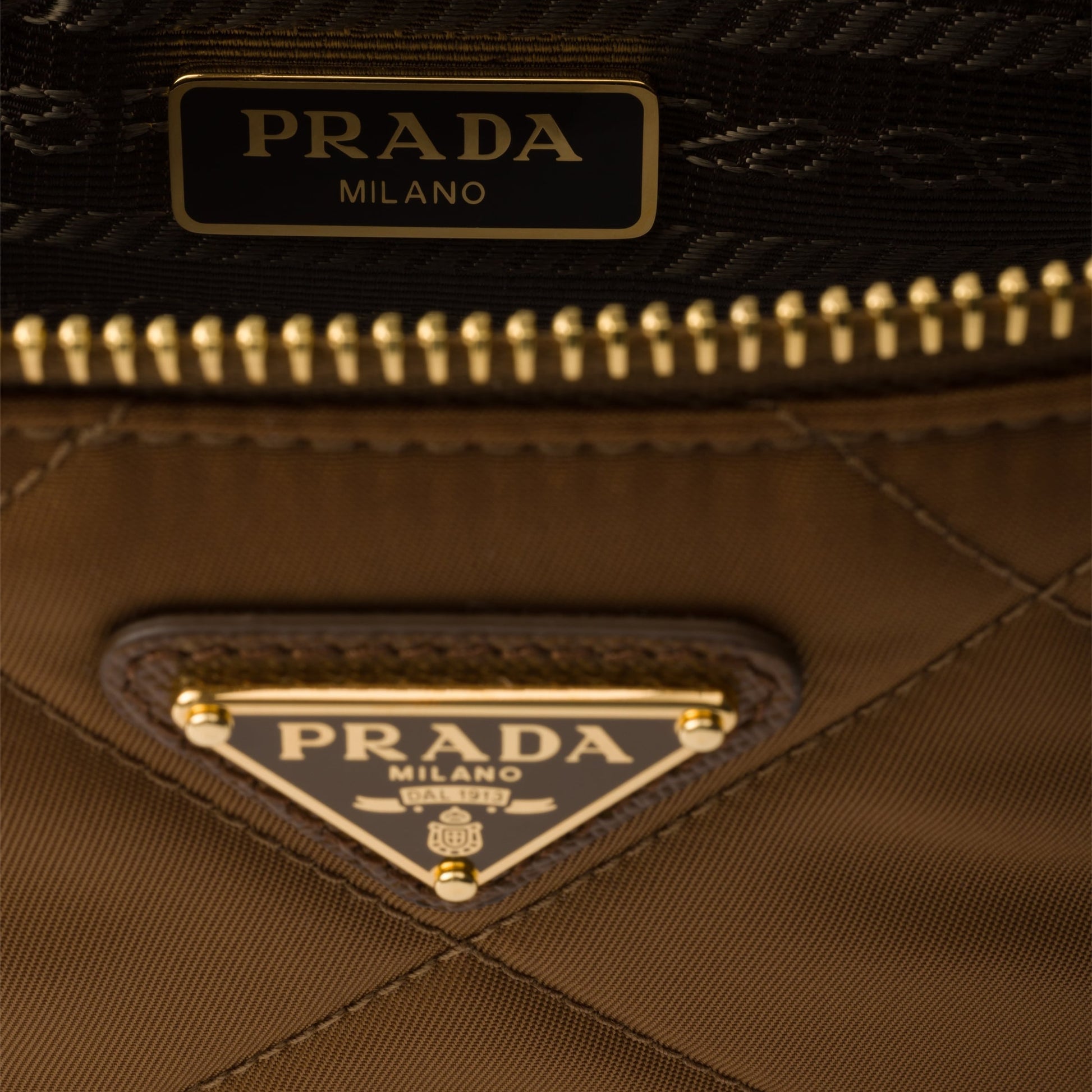 Close-up of a Prada handbag with gold accents and Prada logo.