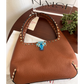 Brown leather handbag with studded details on a wooden table