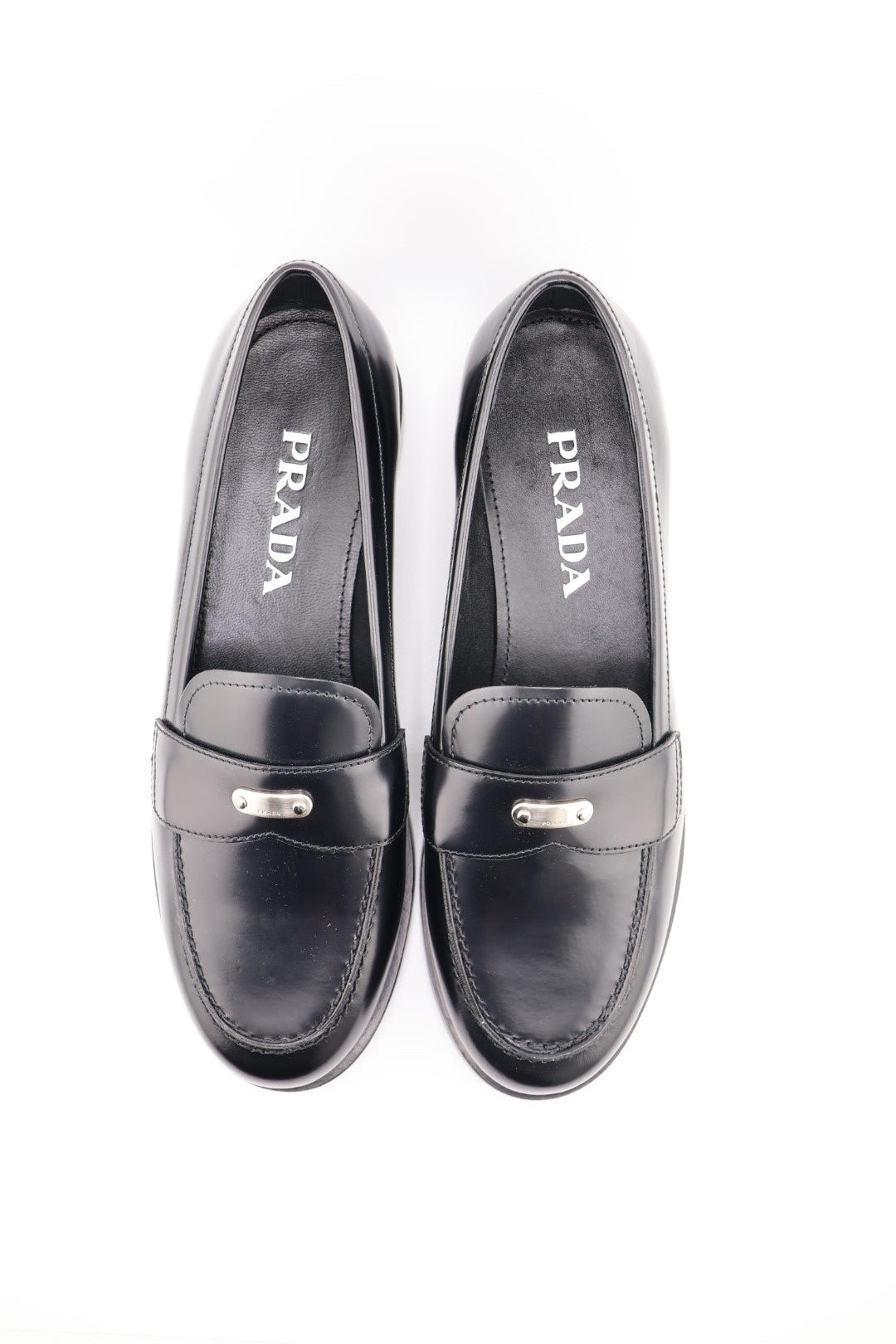 Pair of black Prada loafers on a white background