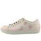 Beige sneakers with pink heart patterns on a white background