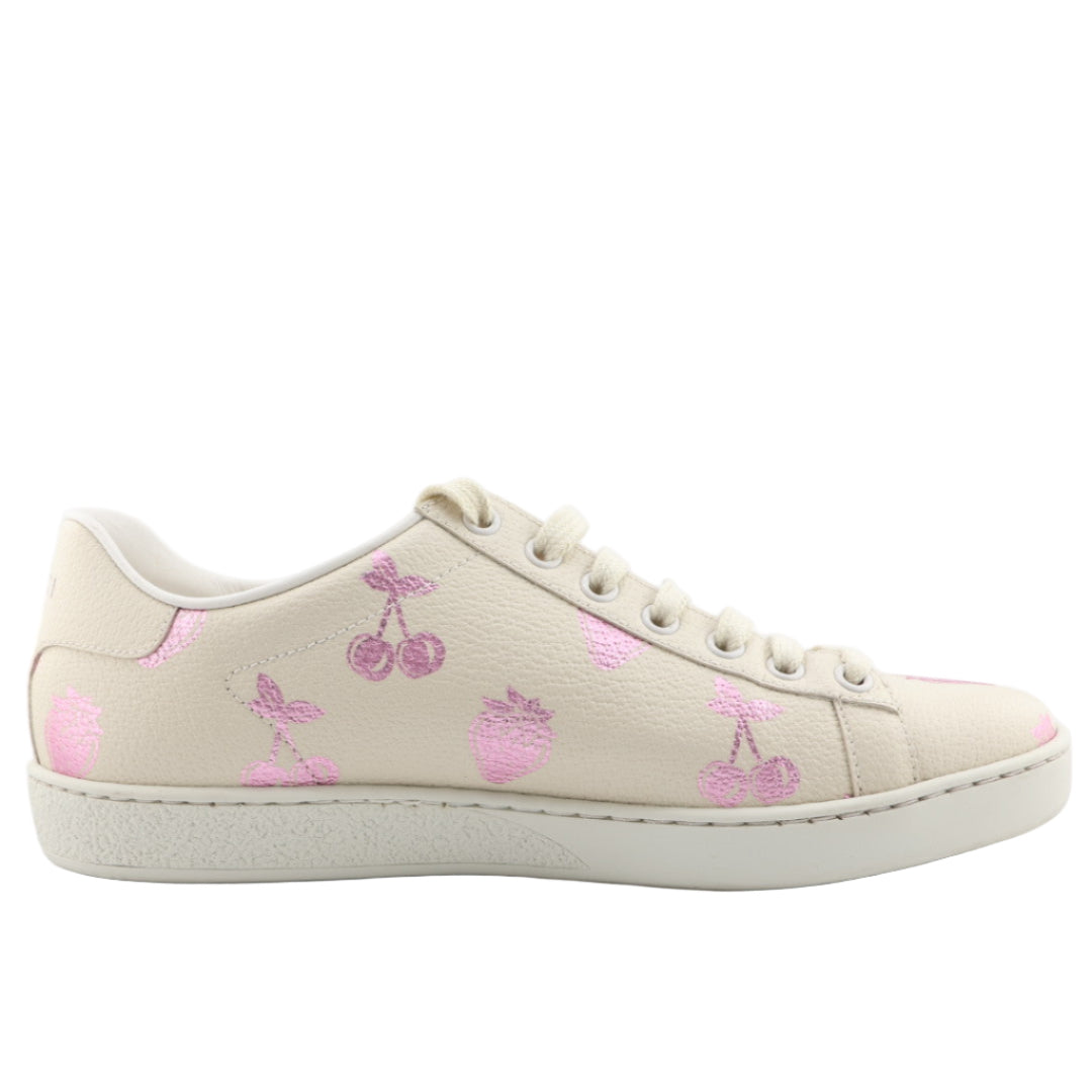 Beige sneaker with pink cherry designs on a white background