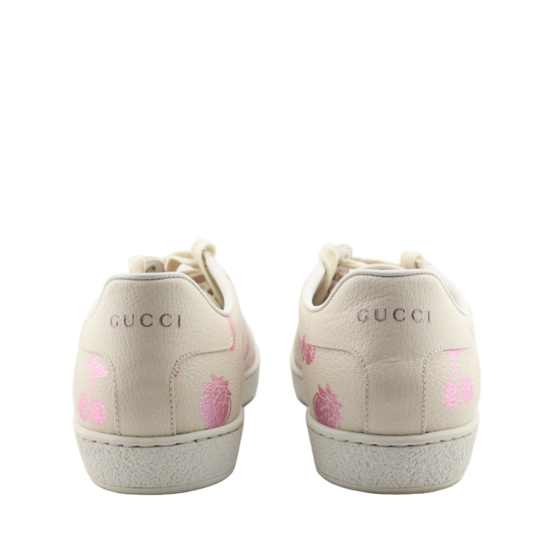 Beige Gucci sneakers with pink heart designs on a white background