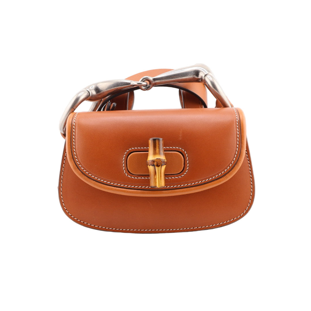 Brown leather handbag with gold clasp on a white background