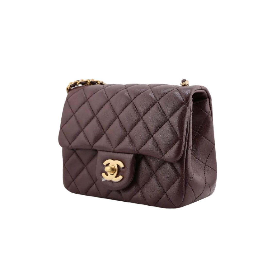 Quilted brown handbag with gold hardware on a white background