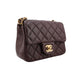 Quilted brown handbag with gold hardware on a white background