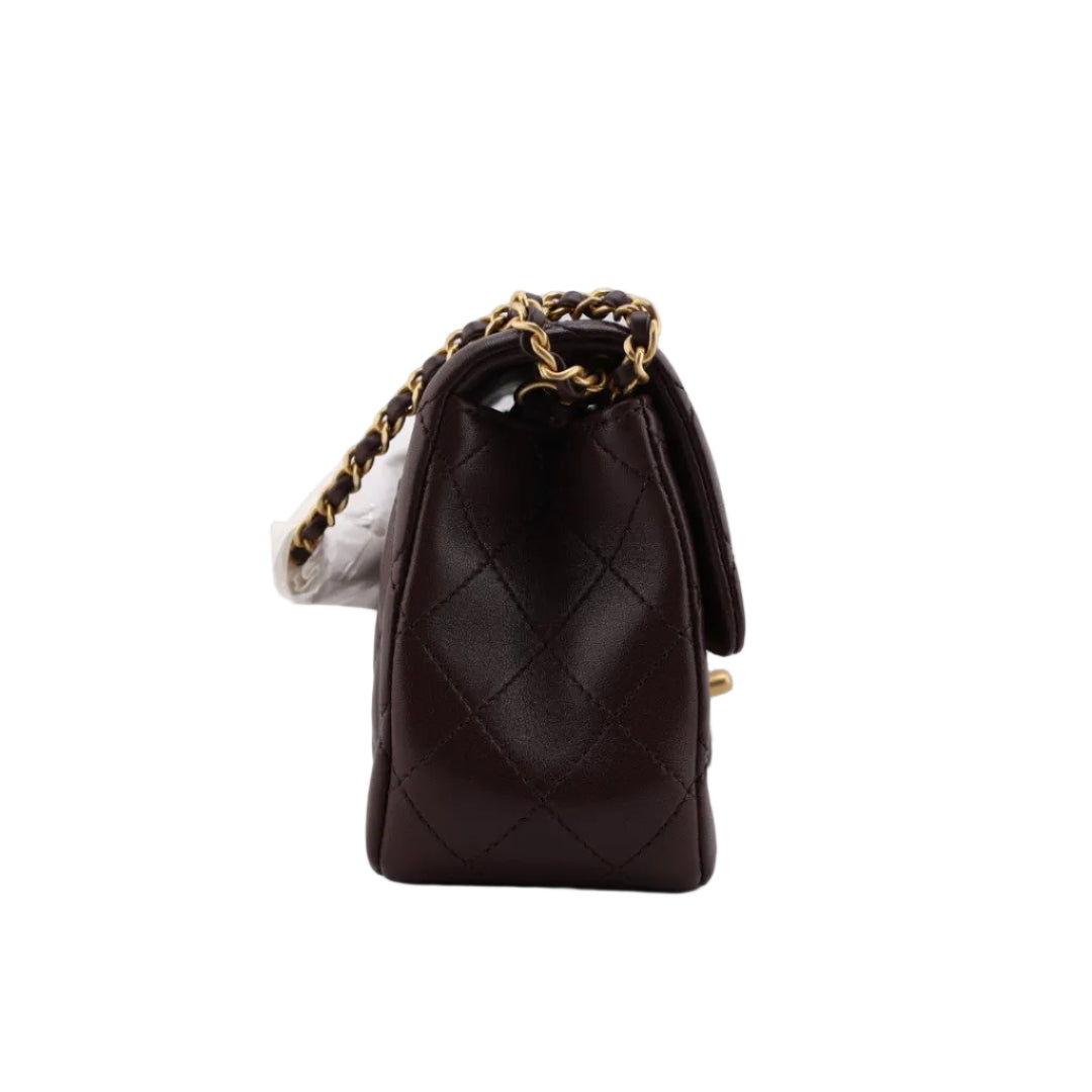 Brown quilted handbag with gold chain on a white background