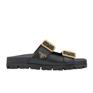 Black sandal with gold buckles on a light gray background