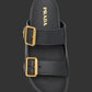 Black sandal with gold buckles and Prada logo on a light gray background