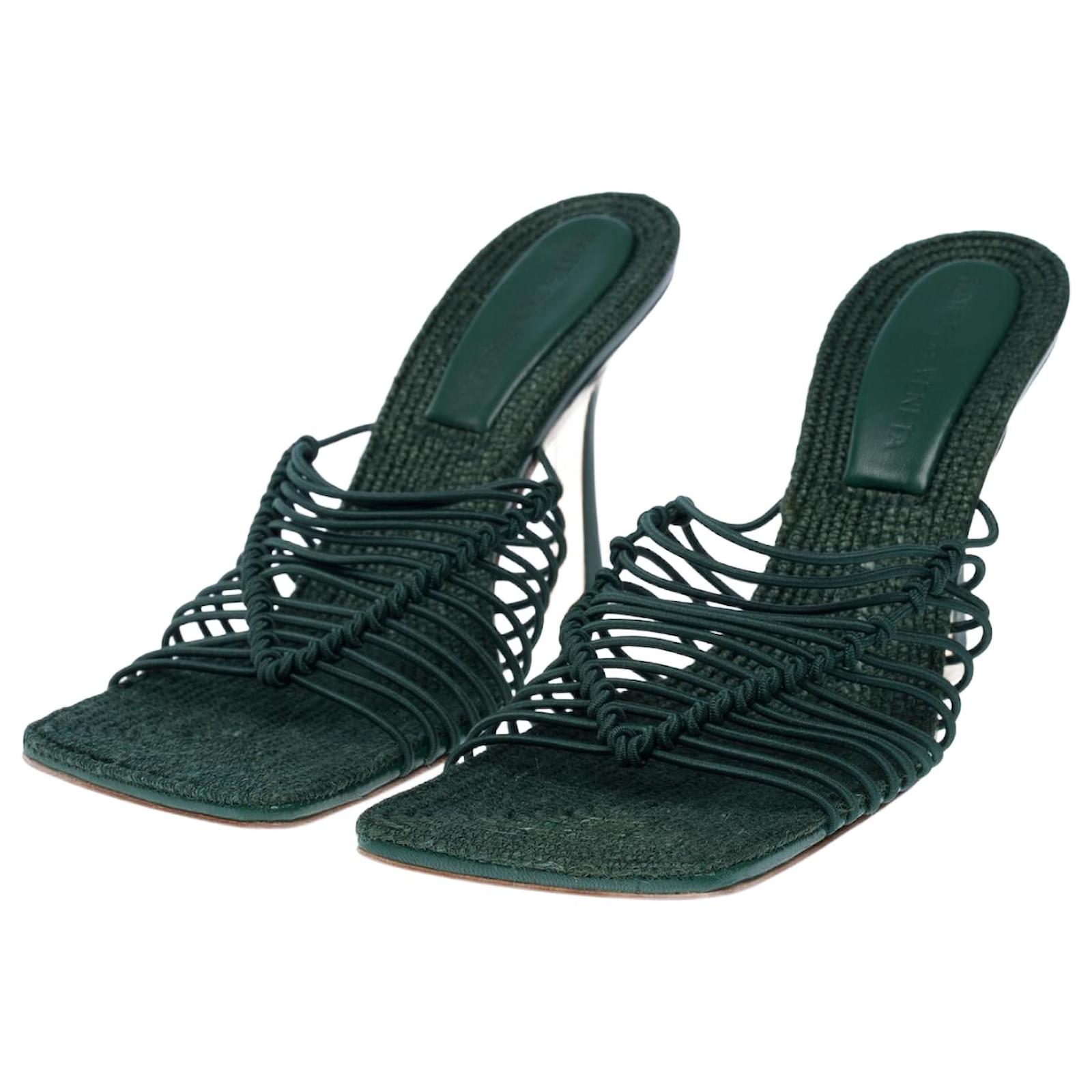 Pair of green strappy sandals on a white background