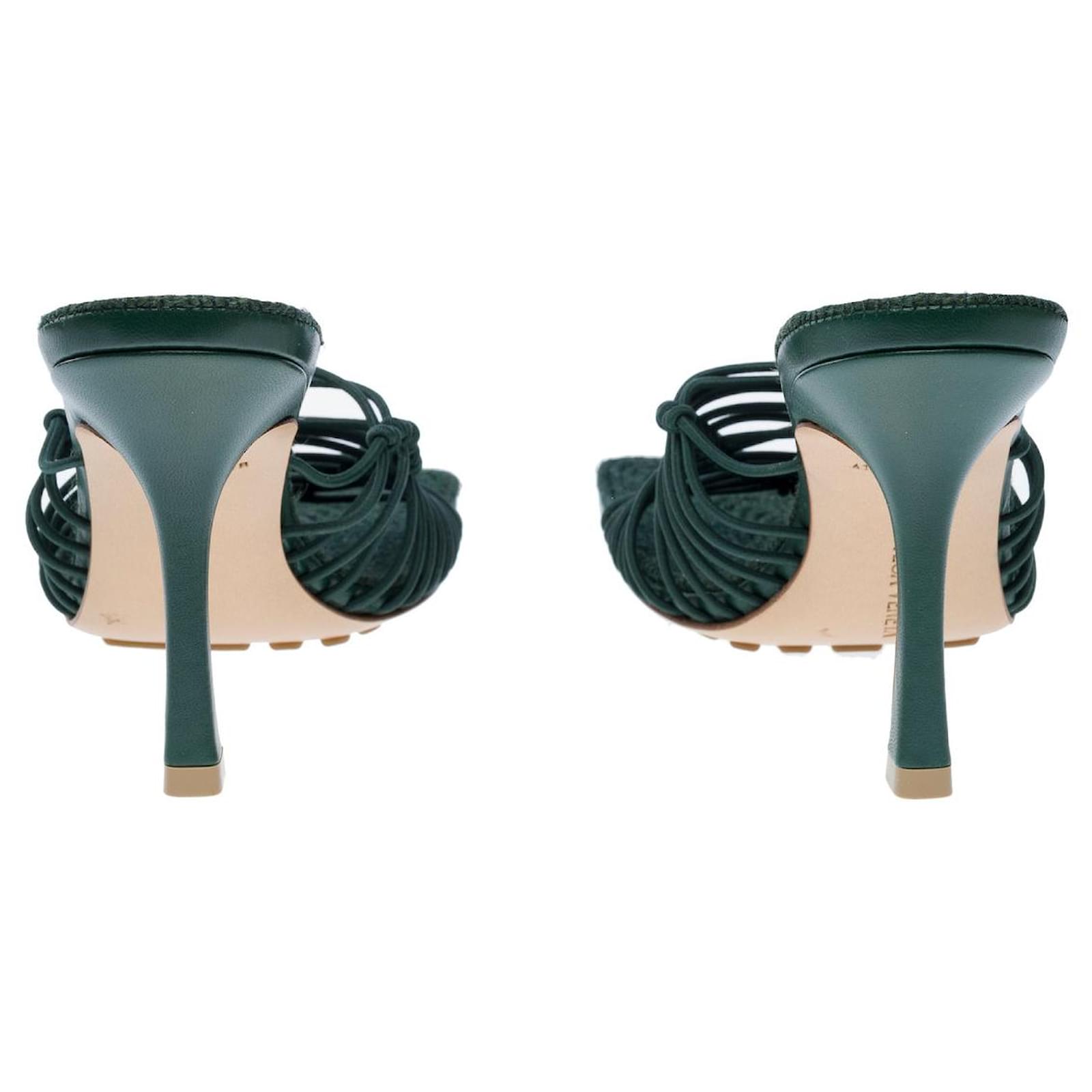 Green high-heeled shoes with ruched straps on a white background