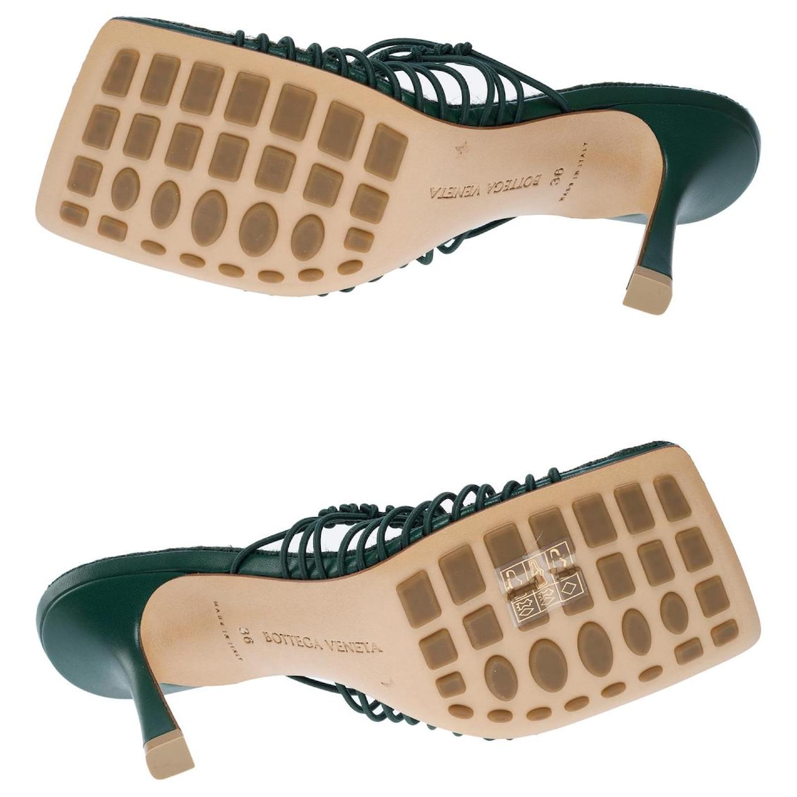 Green high-heeled shoes with braided design on a white background