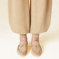 Beige loafers worn with beige pants on a light background