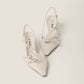 White pointed-toe slingback shoes with 'Miu Miu' branding on a light gray background