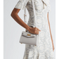 Versace handbag with a woman wearing a patterned dress on a white background