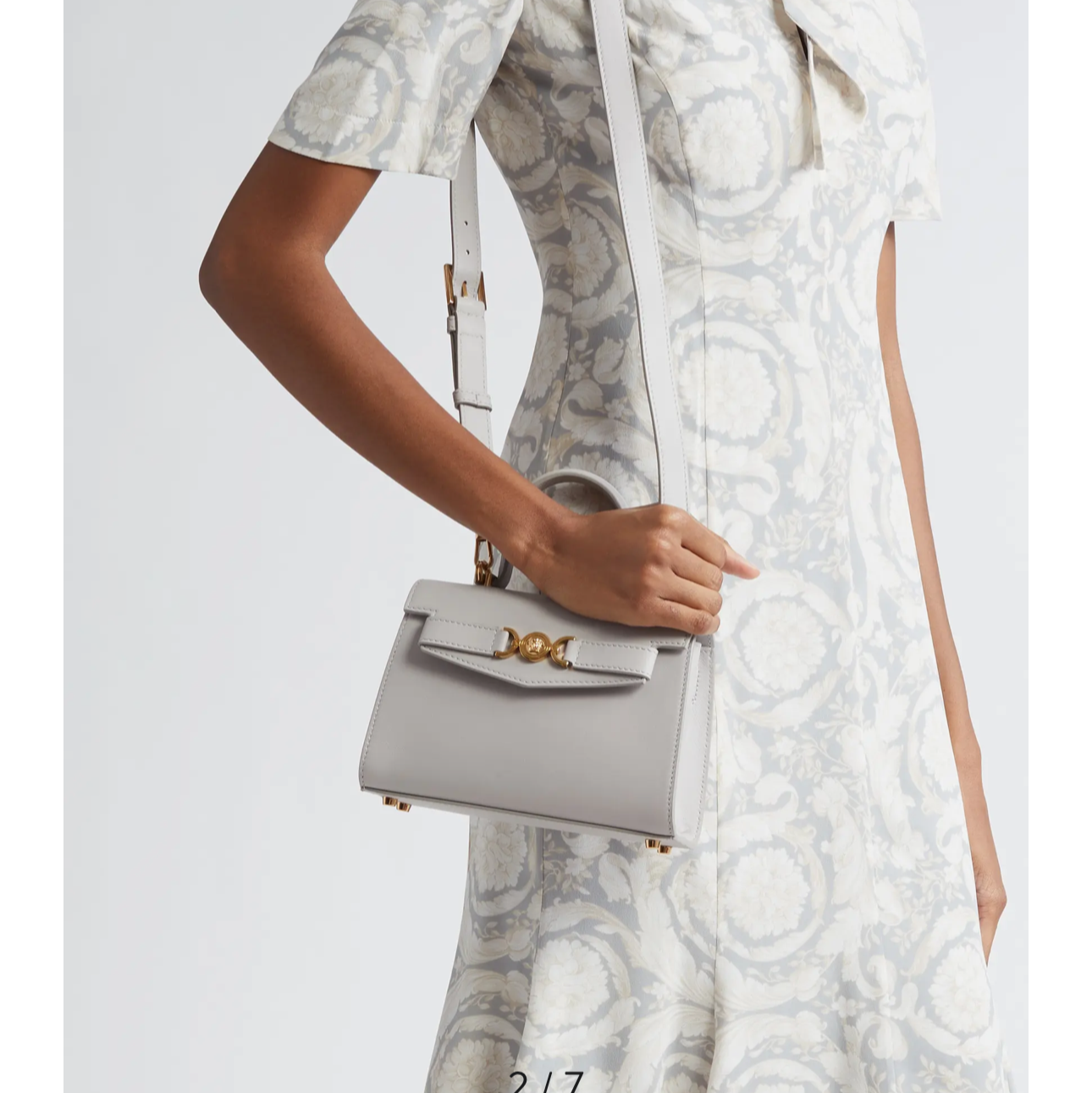 Versace handbag with a woman wearing a patterned dress on a white background
