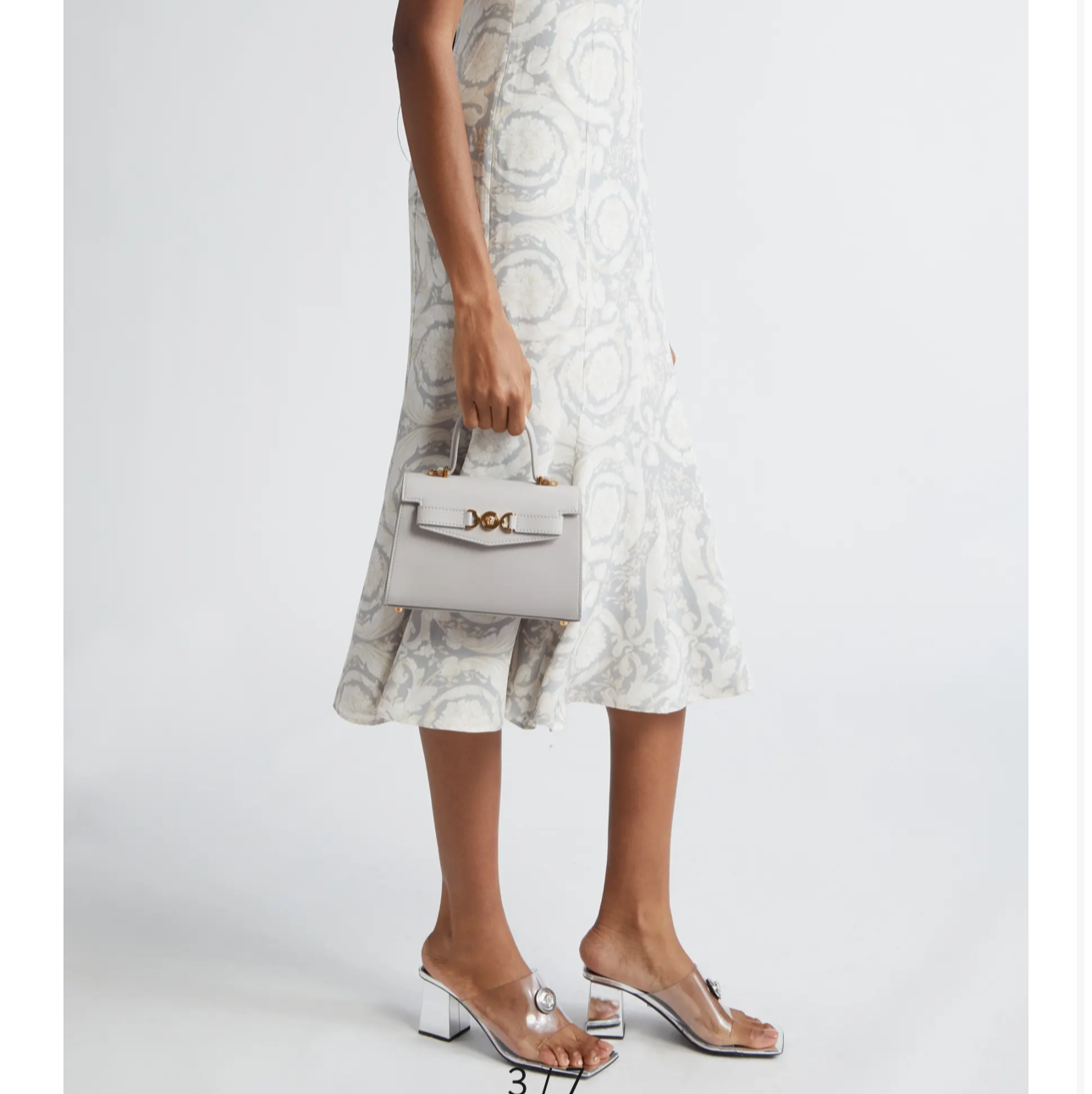 Woman wearing a pearl grey gold Versace dress on a white background