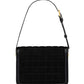 Black quilted handbag with a strap on a white background