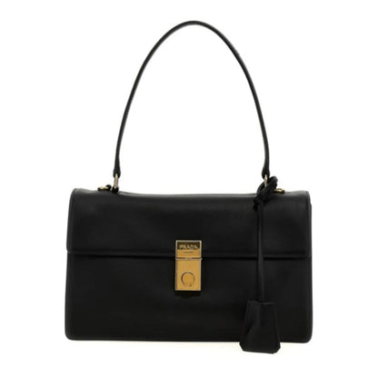 A black leather handbag with a structured rectangular shape, a single top handle, a front flap, and a gold-tone lock closure. A black leather tag hangs from the side, and the bag is photographed against a plain white background.