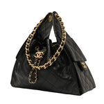 Black Chanel quilted handbag with gold chain and hardware on a light gray background
