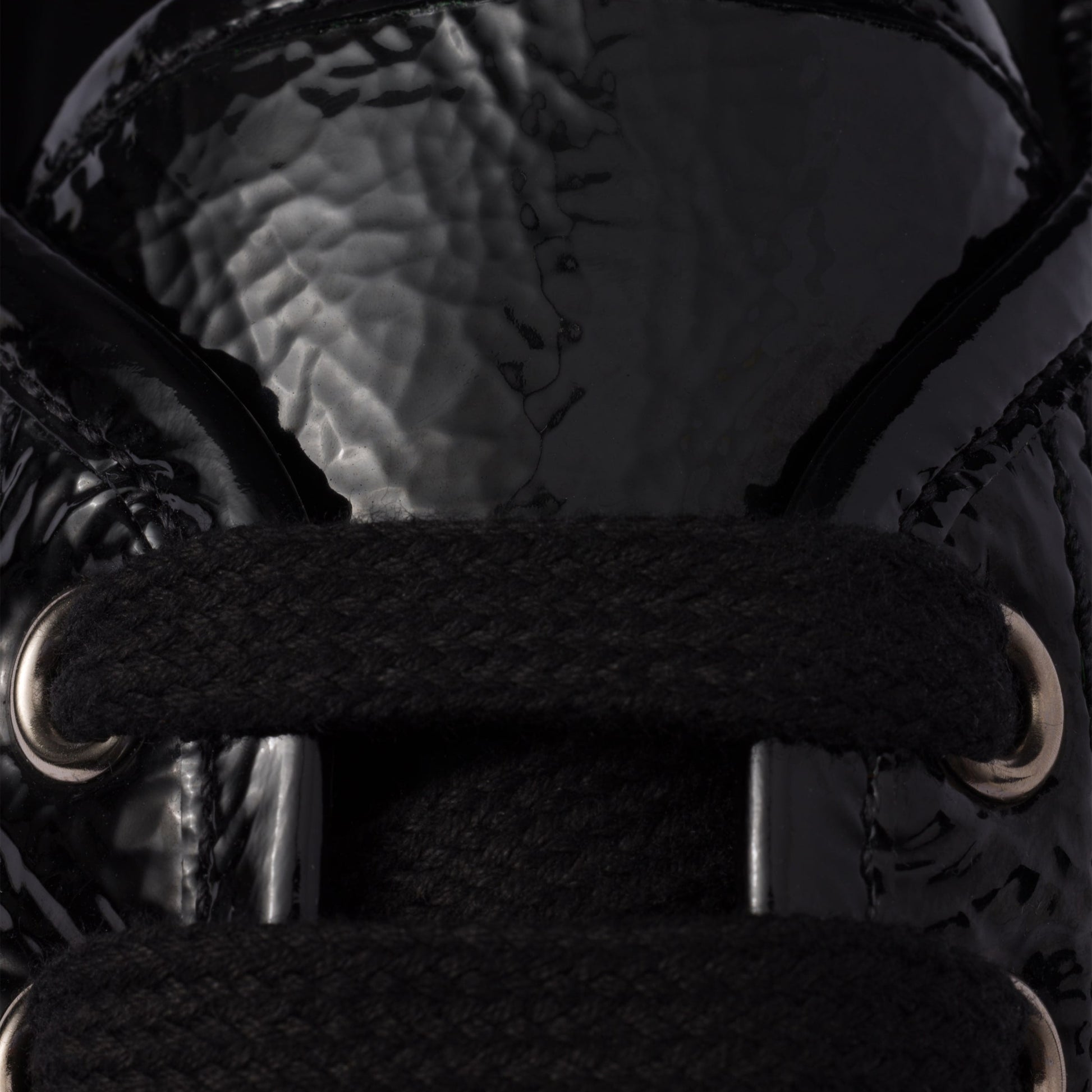 Close-up of a black winter boot with textured sole and lace-up design.