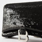Black sequin clutch with a silver clasp on a white background